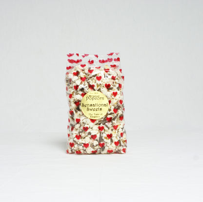 Bag of popcorn with red heart patterns on a light gray background